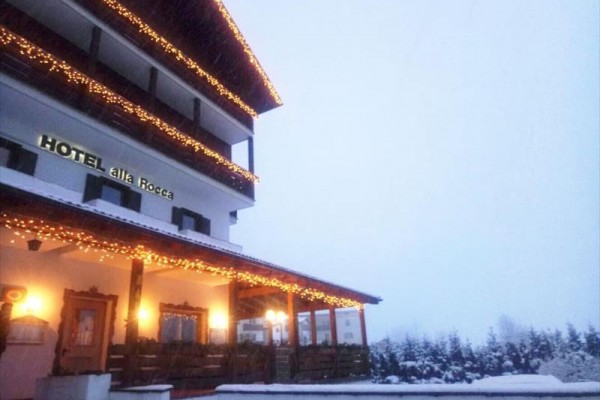 Hotel ozdobiony świątecznymi światłami z widokiem na zaśnieżony krajobraz.