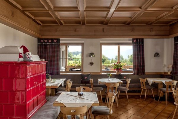 Tradycyjne wnętrze restauracji z drewnianymi meblami i czerwoną kaflową piec.