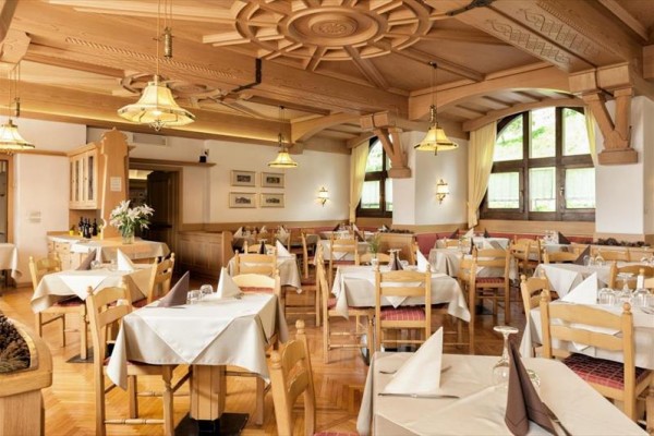 Restauracja z drewnianym sufitem i nakrytymi stołami.