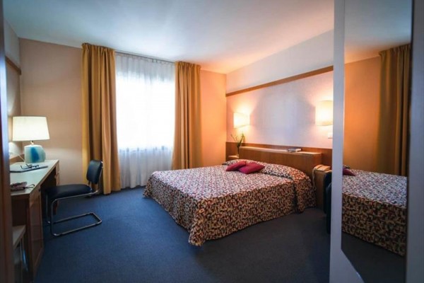 Pokój hotelowy z łóżkiem małżeńskim, biurkiem i krzesłem.