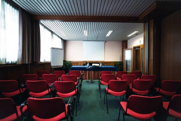 Sala konferencyjna z czerwonymi krzesłami i projektorem.
