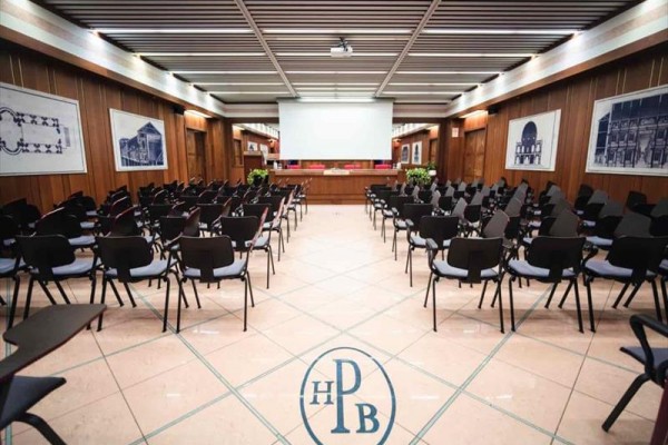 Sala konferencyjna z ekranem projekcyjnym i stołem organizacyjnym.