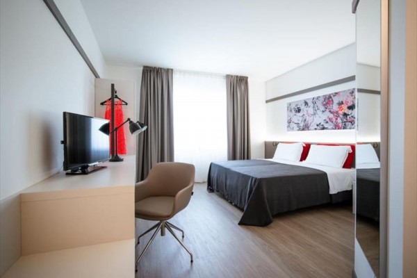 Nowoczesny pokój hotelowy z łóżkiem małżeńskim, telewizorem i biurkiem.