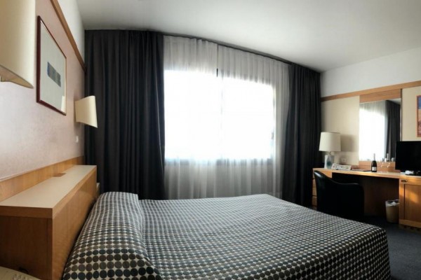 Nowoczesny pokój hotelowy z łóżkiem, biurkiem i telewizorem.