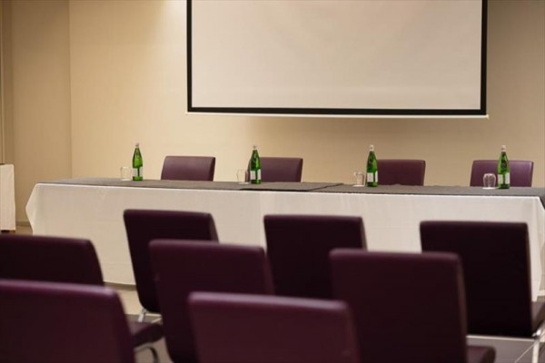 Sala konferencyjna z pustym stołem i butelkami wody.