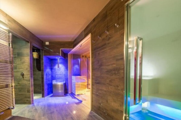 Nowoczesne spa z drewnianą boazerią, sauną i kolorowym oświetleniem.