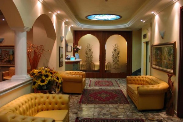Eleganckie lobby hotelowe z wygodnymi żółtymi sofami i dekoracją kwiatową.