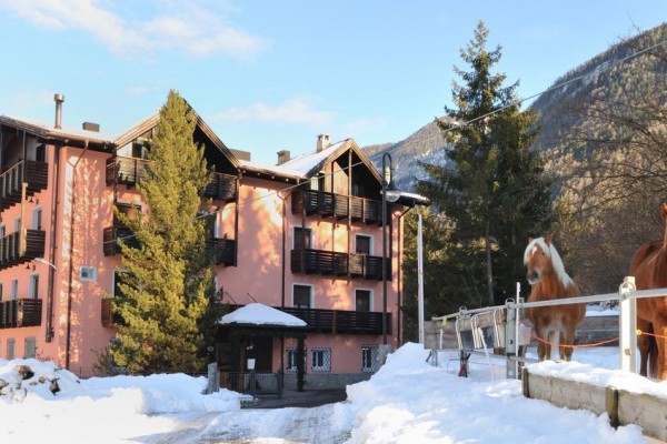 Różowy górski hotel z dwoma końmi na zaśnieżonym stoku.