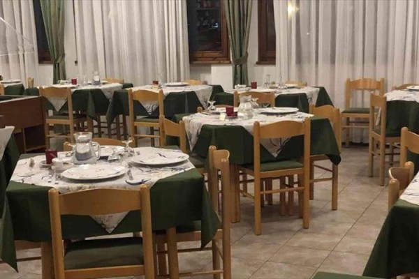 Restauracja z drewnianymi krzesłami i zielonymi obrusami.