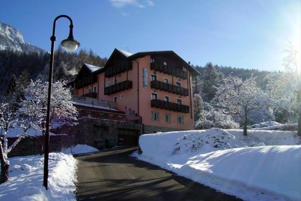 Hotel otoczony śniegiem i ośnieżonymi drzewami w słoneczną pogodę.