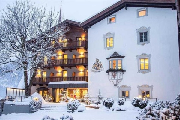 Zaśnieżony hotel z oświetlonymi oknami i ozdobioną fasadą.