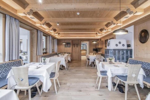 Restauracja z drewnianym wnętrzem z nakrytymi stołami i niebieskimi tapicerowanymi krzesłami.