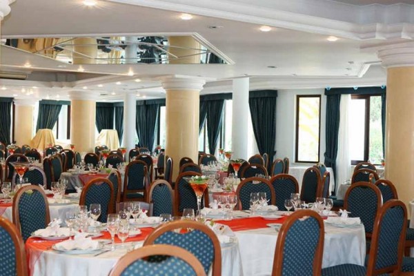 Elegancka restauracja z okrągłymi stołami, białymi obrusami i niebieskimi krzesłami.