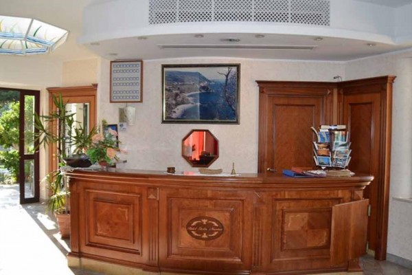 Recepcja hotelowa z drewnianym blatem i obrazami na ścianie.