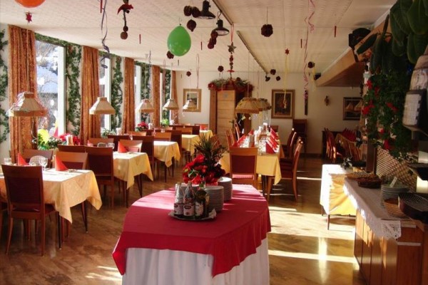 Świątecznie udekorowana restauracja z nakrytymi stołami i świecącymi dekoracjami.