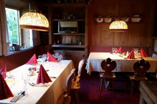 Wnętrze restauracji z dwoma stołami z czerwonymi serwetkami, ozdobione szklankami i sztućcami.