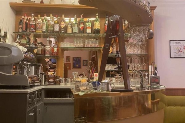 Barowy kontuar z ekspresem do kawy, butelkami alkoholu i szklankami.