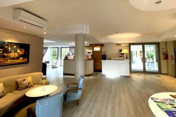 Nowoczesna recepcja hotelowa z sofą, fotelami i barem w rogu.