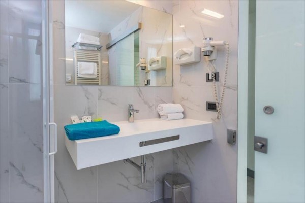 Nowoczesna łazienka hotelowa z dużym lustrem i elegancką umywalką.