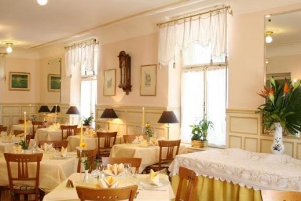 Stylowa restauracja z nakrytymi stołami i kwiatową dekoracją.