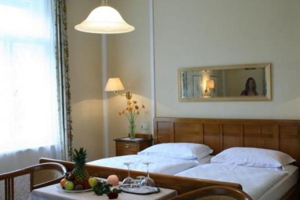 Przytulny pokój hotelowy z podwójnym łóżkiem, stołem z kieliszkami i owocami.