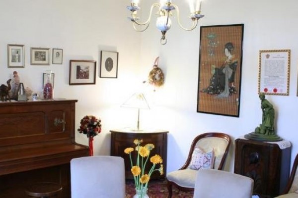 Klasyczny salon z pianinem, fotelami i obrazami na ścianach.  