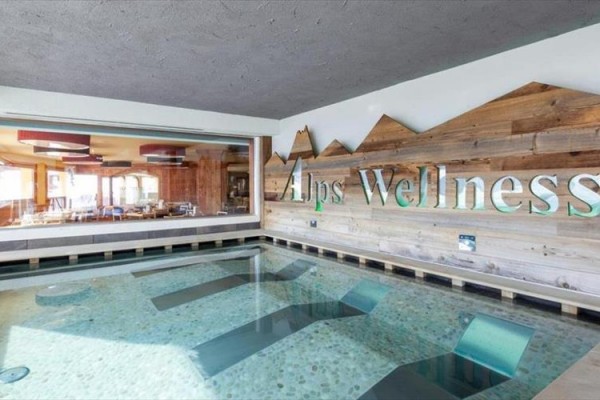 Wewnętrzny basen z napisem Alps Wellness na drewnianej ścianie.