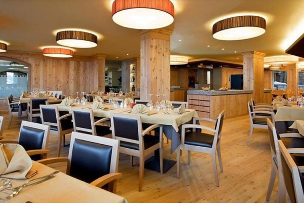Przestronna restauracja z drewnianym wnętrzem i nakrytymi stołami.