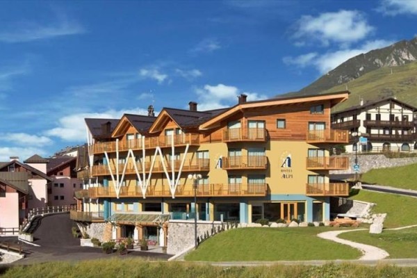 Hotel z drewnianą okładziną i balkonami w górskim krajobrazie.