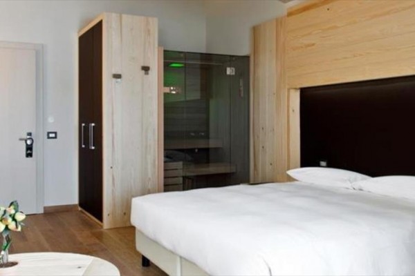 Nowoczesny pokój hotelowy z łóżkiem i kabiną prysznicową.
