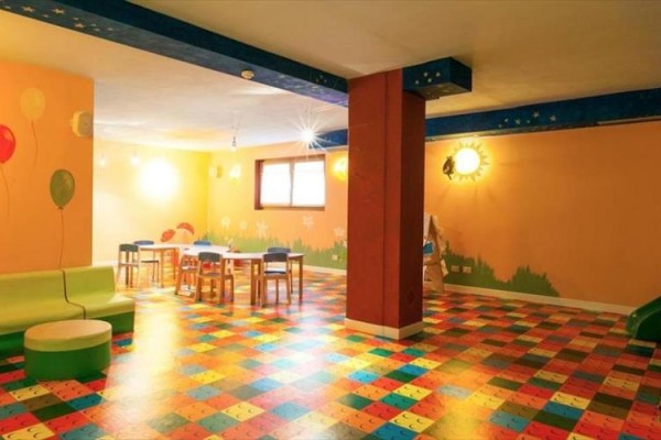 Sala zabaw z kolorową podłogą i meblami dla dzieci.