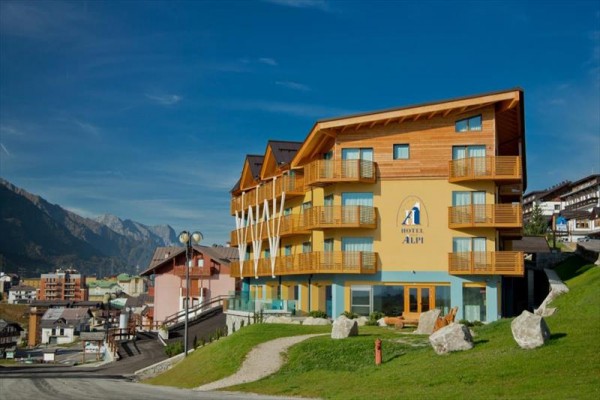 Drewniany hotel na zboczu z widokiem na górską wioskę i góry.
