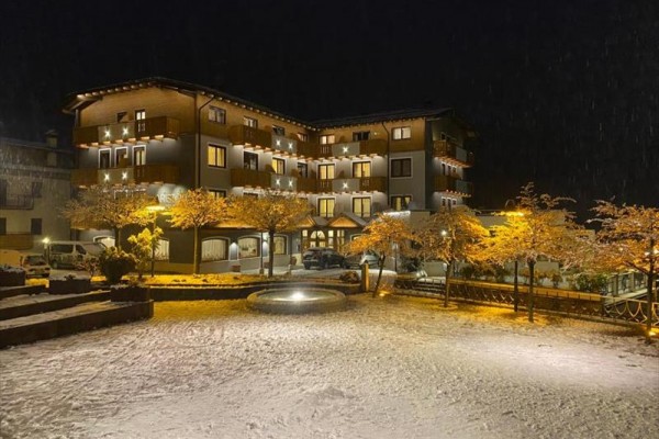 Nocny widok na oświetlony budynek hotelu otoczony zaśnieżonym krajobrazem.