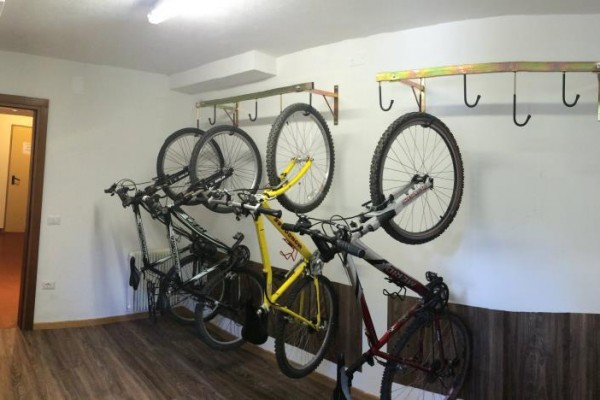 Rowerownia z pięcioma rowerami zawieszonymi na ścianie.