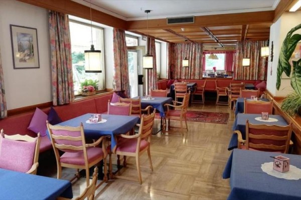 Restauracja z drewnianymi krzesłami i niebieskimi obrusami.
