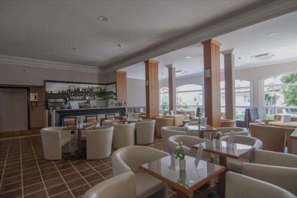 Nowoczesny hotelowy bar z białymi krzesłami i szklanymi stołami.
