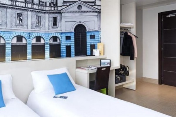 Pokój hotelowy z dwoma pojedynczymi łóżkami i dekoracją na ścianie.