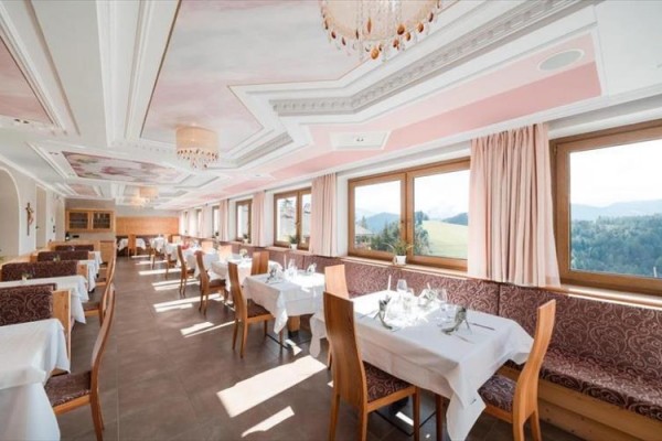 Jasna restauracja z nakrytymi stołami, widokiem na krajobraz i różowym sufitem.