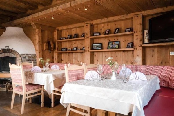Stylowa restauracja z drewnianym wnętrzem, przygotowanymi stołami i kominkiem.