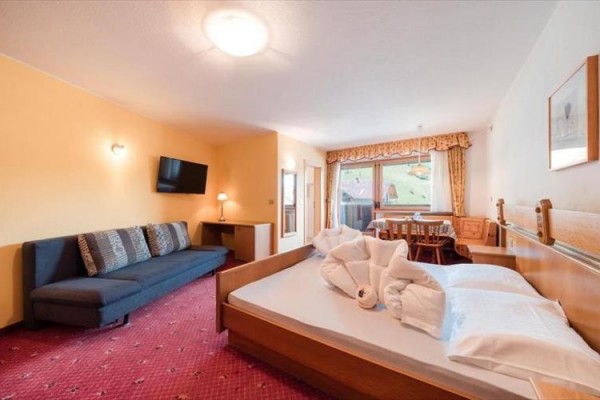 Przestronny pokój hotelowy z łóżkiem małżeńskim, sofą, telewizorem i widokiem z okna.