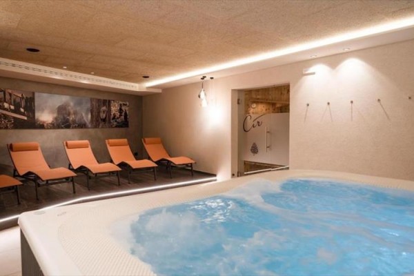 Jacuzzi i pomarańczowe leżaki w nowoczesnym pokoju relaksacyjnym.