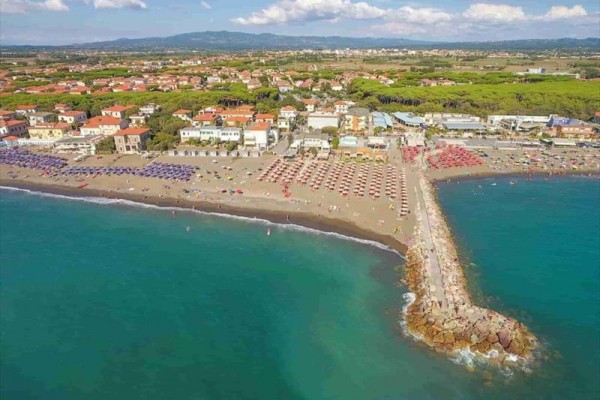 Widok z góry na plażę otoczoną parasolami obok miasta nad morzem.