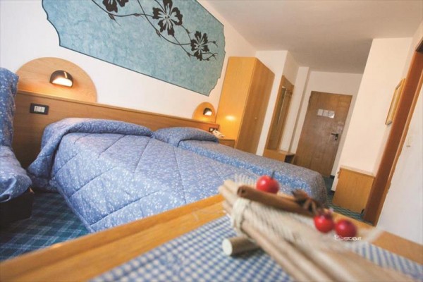 Pokój hotelowy z dwoma oddzielnymi łóżkami i niebieską dekoracją na ścianie.