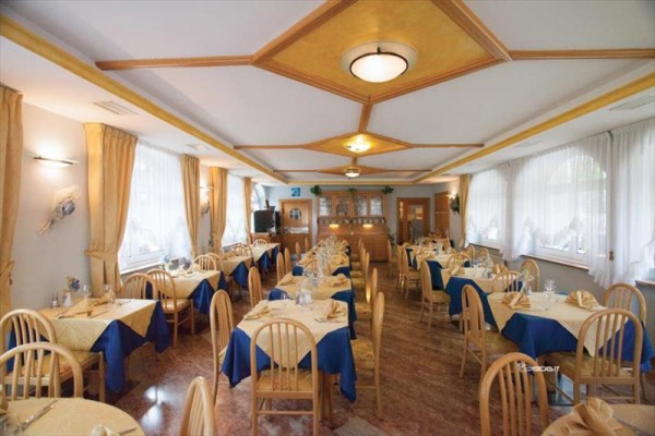 Eleganckie wnętrze restauracji z drewnianymi meblami i niebiesko-beżowymi obrusami.