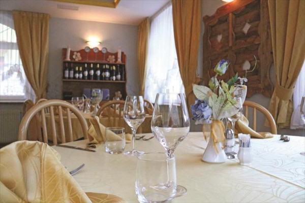 Restauracja z elegancko nakrytym stołem, kieliszkami i ozdobą kwiatową.