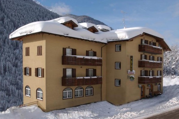 Trzypiętrowy hotel w ośnieżonym górskim krajobrazie.