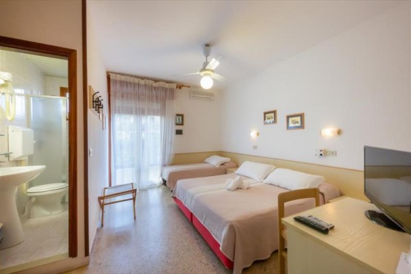 Pokój hotelowy z dwoma łóżkami, telewizorem i łazienką.