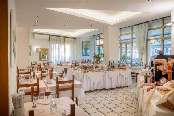 Restauracja z nakrytymi stołami i bufetem pośrodku.