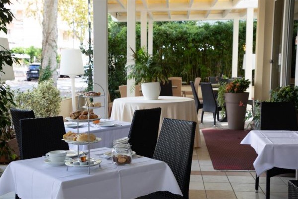 Ogródkowa restauracja z nakrytymi stolami i roślinami wokół.