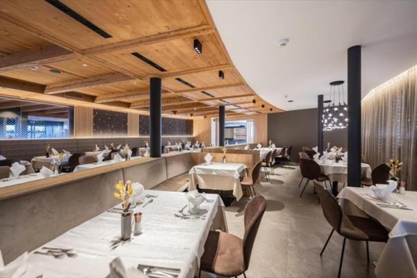 Restauracja z elegancko nakrytymi stołami i drewnianym sufitem.